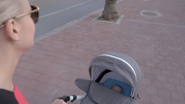 Young-mother-walking-with-baby-sleeping-in-pram