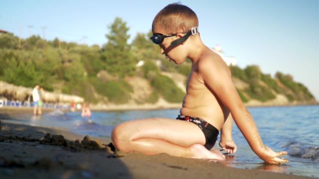 Kind-sitzt-auf-dem-Sand-und-Meereswellen-waschen-ihn-genießen