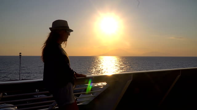 Silhouette-of-young-attractive-woman-watching-sunset-at-cruising-ship-in-the-sea