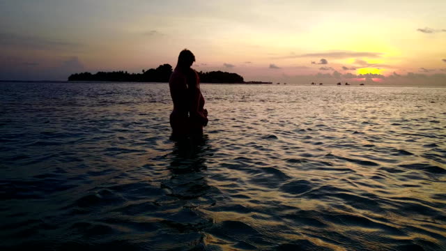 v04139-vuelo-drone-vista-aérea-de-Maldivas-playa-2-personas-pareja-hombre-mujer-amor-romántico-puesta-de-sol-salida-del-sol-en-la-isla-de-paraíso-tropical-soleado-con-cielo-azul-aqua-agua-mar-4k