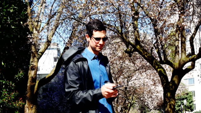 Man-using-mobile-phone-while-having-coffee-in-park-4k