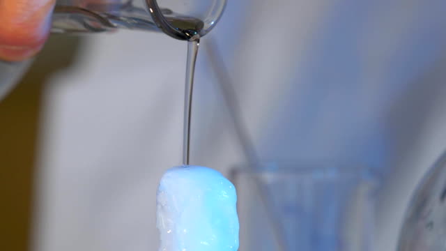 Chemische-Experimente.-Die-Flüssigkeit-strömt-aus-dem-Glas-auf-den-schwarzen-Tisch-und-sofort-gefriert.-sofort-einfrieren-Flüssigkeit