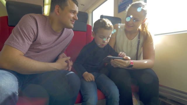 Family-with-child-traveling-by-train-and-using-cell