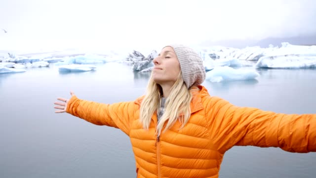 Junge-Frau-Arme-ausgestreckt-an-die-Gletscherlagune-Islands-genießen-Freiheit-in-der-Natur-umarmt-Leben-und-Vitalität