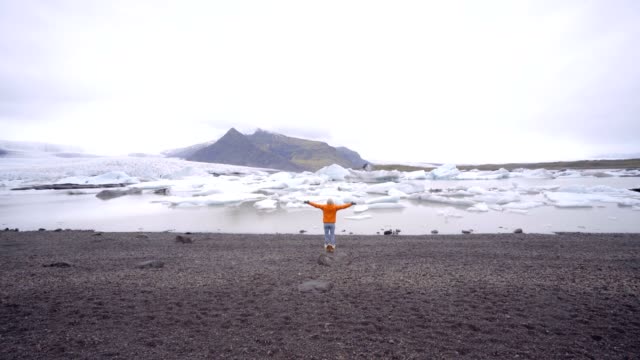 Brazos-de-la-joven-extendidos-en-la-laguna-de-glaciar-en-Islandia
