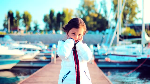 Little-baby-girl-dreams-about-something-on-the-pier-for-boats-and-yachts