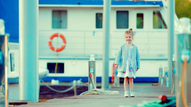 Girl-child-is-walking-along-the-pier-for-yachts-and-boats