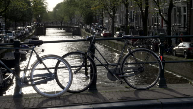 Fahrräder,-die-Silhouette-auf-einer-Brücke-über-einen-Kanal-in-amsterdam
