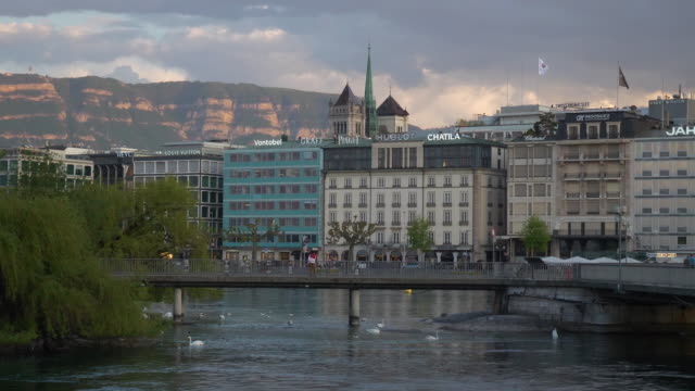 puente-sobre-el-río-al-atardecer-cielo-Ginebra-ciudad-Bahía-lenta-panorama-4k-Suiza