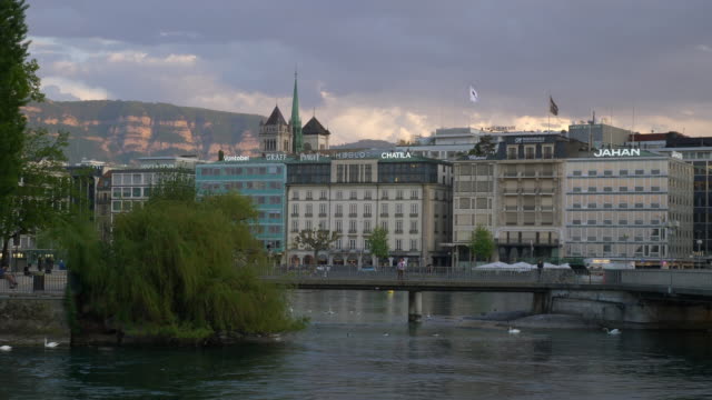 puente-sobre-el-río-al-atardecer-cielo-Ginebra-ciudad-Bahía-lenta-panorama-4k-Suiza