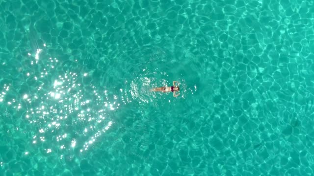 Vista-aérea-de-una-mujer-nadando-en-el-mar-de-la-isla-de-Atokos,-Grecia
