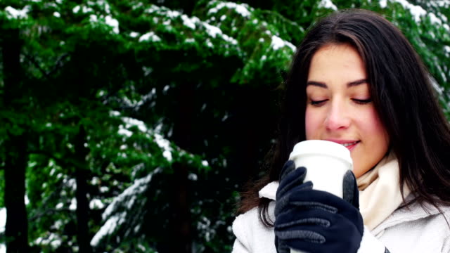 Woman-in-warm-clothing-having-coffee-during-snowfall