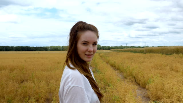 Joven-mujer-caminando-por-un-campo-de-hierba-dorada
