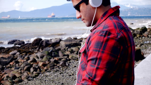 Man-in-headphones-using-digital-tablet-at-seaside-4k