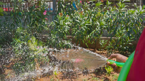 Close-Up-Of-Person-Watering-Plants-in-Garden-With-Hose-In-Mumbai-India
