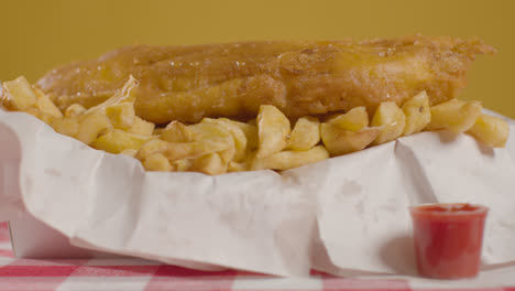 Close-Up-Studio-Shot-Of-Traditional-British-Takeaway-Meal-Of-Fish-And-Chips-With-Vinegar