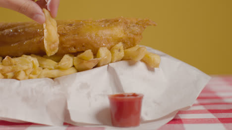 People-Using-Fingers-To-Eat-Traditional-British-Takeaway-Meal-Of-Fish-And-Chips-With-Vinegar