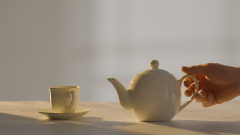Studio-Shot-Of-Person-Making-Traditional-British-Cup-Of-Tea-Using-Teapot
