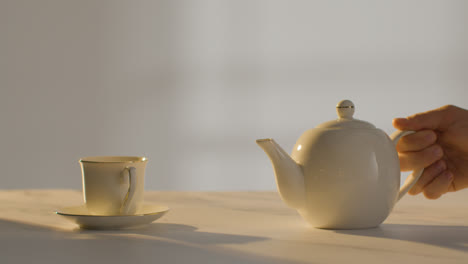Studio-Shot-Of-Person-Making-Traditional-British-Cup-Of-Tea-Using-Teapot-1