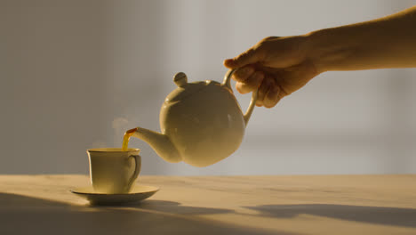 Studio-Shot-Of-Person-Making-And-Pouring-Traditional-British-Cup-Of-Tea-Using-Teapot-1