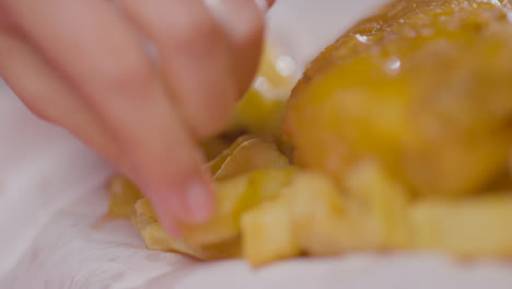 Close-Up-Of-Person-Eating-Traditional-British-Takeaway-Meal-Of-Fish-And-Chips-Using-Fingers