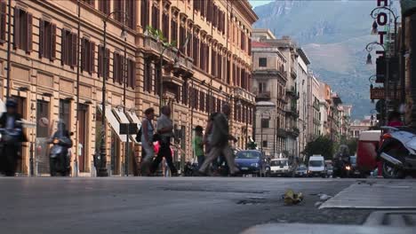 Old-buildings-line-a-busy-street-with-vehicles-and-pedestrians-passing-through-Palermo-Italy--1