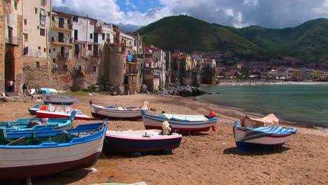 Boats-on-a-beach-next-to-the-ocean-and-houses-in-Cefalu-Italy--