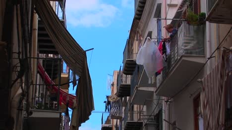 A-man-hangs-clothing-from-his-balcony-across-from-other-apartment-buildings-in-Cefalu-Italy----