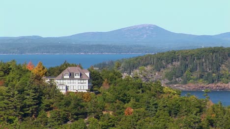 A-house-and-islands-are-seen-in-the-distance-of-a-forest-in-Bar-Harbor-Maine