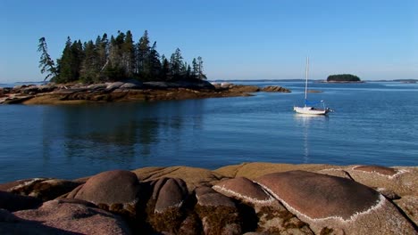 A-sailboat-is-at-anchor-in-a-bay-offshore-a-lobster-village-in-Stonington-Maine