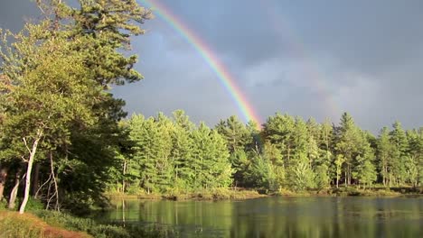 A-rainbow-over-a-forest-and-near-a-lake-in-Rural-Maine--1