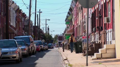 A-woman-walks-down-a-sidewalk-near-vehicles-parked-along-brick-buildings-in-Philadelphia-Pennsylvania