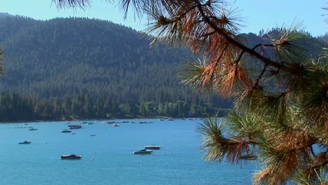 Los-Barcos-Flotan-Sobre-El-Agua-En-El-Lago-Tahoe-Rodeado-Por-Colinas-Cubiertas-De-árboles-En-Las-Montañas-De-Sierra-Nevada