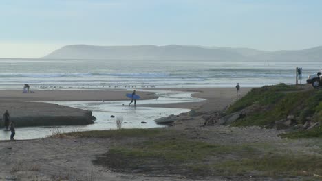 Un-Surfista-Cruza-Un-Estuario-A-Lo-Largo-De-La-Costa-Central-De-California.
