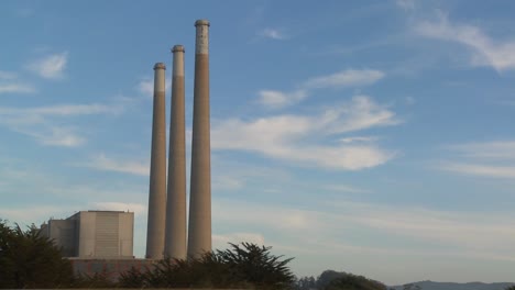 A-time-lapse-shot-of-clouds-moving-behind-the-smokestacks-of-a-power-plant