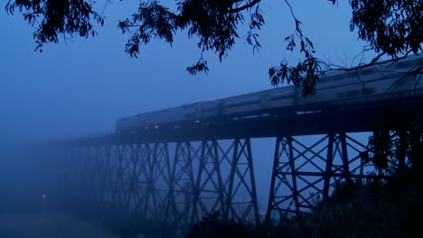 An-Amtrak-passenger-trains-speeds-across-a-bridge-in-the-fog-at-night