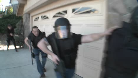 DEA-or-SWAT-officers-with-arms-drawn-perform-a-drug-raid-on-a-house