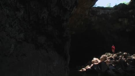 Wunderschöner-Schwenk-über-Eine-Tiefe-Dunkle-Höhle,-Um-Einen-Massai-Krieger-Zu-Enthüllen,-Der-In-Einem-Lichtbecken-In-Kenia-Steht