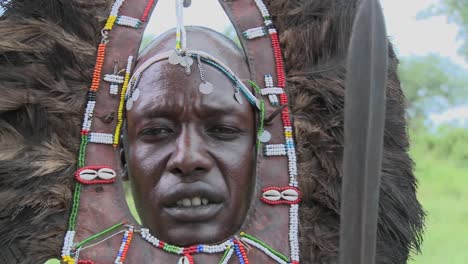 Dolly-right-to-reveal-Masai-warrior-face-in-full-headdress-beads-and-spear