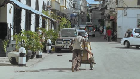 A-man-pushes-a-handcart-up-a-narrow-boulevard-in-Stone-Town-Zanzibar