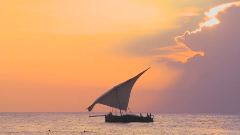 A-beautiful-shot-of-a-dhow-sailboat-sailing-along-the-coast-of-Zanzibar-against-a-beautiful-sunset