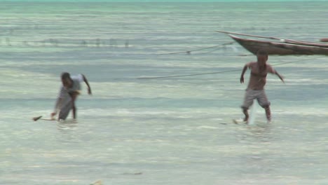 Boys-make-toy-sailboats-and-sail-them-through-the-tide-on-a-tropical-island