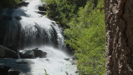 Eine-Bewegende-Aufnahme-An-Einem-Baum-Vorbei,-Um-Einen-Wunderschönen-Alpinen-Wasserfall-Zu-Enthüllen-2