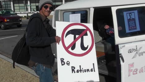 A-man-holds-a-sign-which-says-be-rational-at-a-campaign-rally