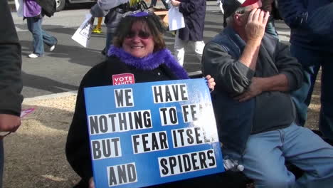 A-woman-holds-a-sign-proclaiming-her-fear-of-spiders