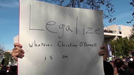 A-man-holds-up-a-sign-saying-legalize-whatever-Christine-ODonnell-is-on-at-the-Jon-Stewart-rally