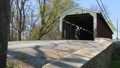 An-Amish-girl-rides-a-foot-powered-scooter-through-a-covered-bridge-in-rural-Lancaster-Pennsylvania