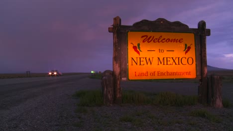 A-roadside-sign-welcomes-visitors-to-New-Mexico-as-cars-pass-at-dusk