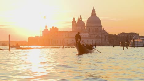 A-gondola-is-rowed-by-a-gondolier-in-front-of-the-setting-sun-in-romantic-Venice-Italy