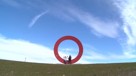 Two-people-sit-on-a-sculpture-of-the-letter-o-against-an-open-sky